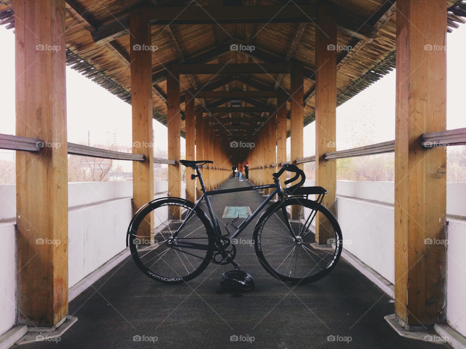 Grayish-black brakeless fixie bicycle standing in the wooden gallery