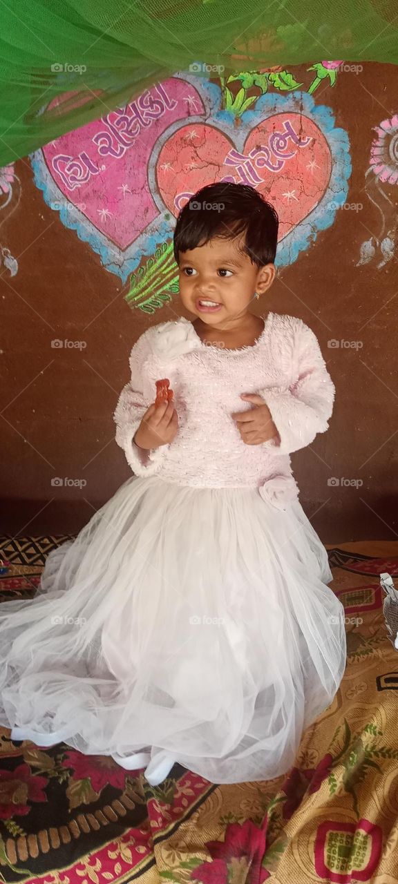 A baby girl. jiyanshi smile is beautiful she looks very attractive. begraound screen it's simple wall upon painting marriage design.