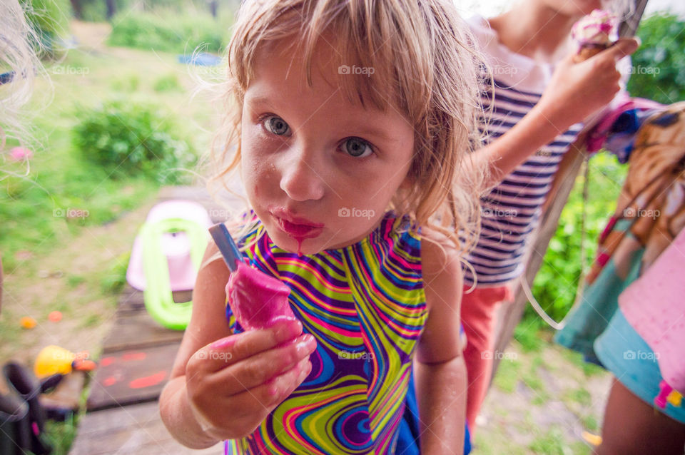 Little girl eating pink ice cream