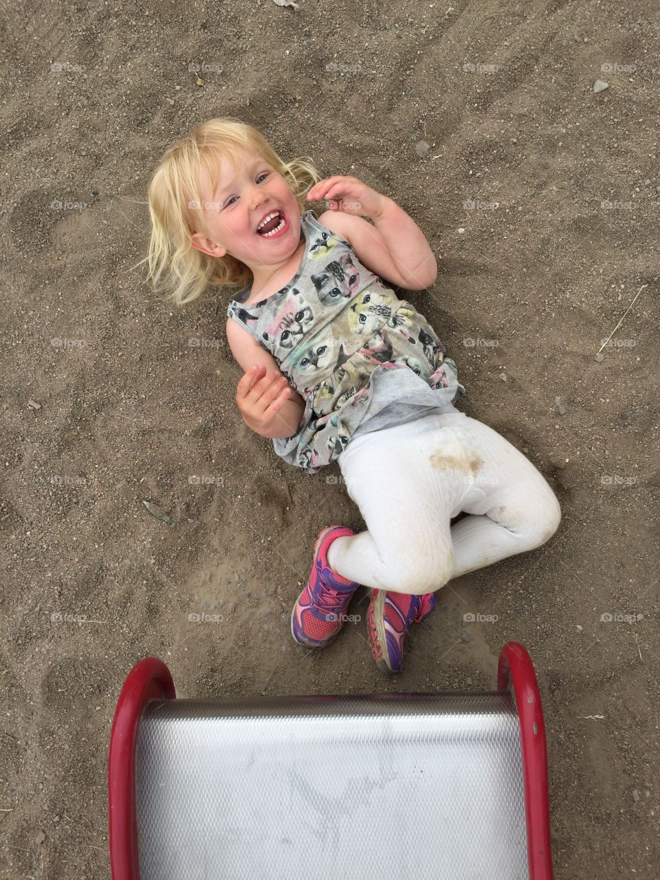 Laughing little girl of two years old, playing in the sandbox.