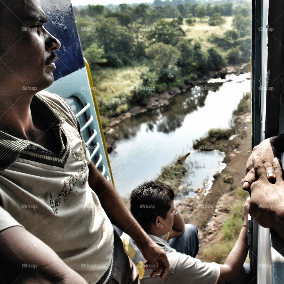 Passengers on Konkan Railway gaze out of moving train door, Goa, India . Passengers on Konkan Railway gaze out of moving train door, Goa, India 