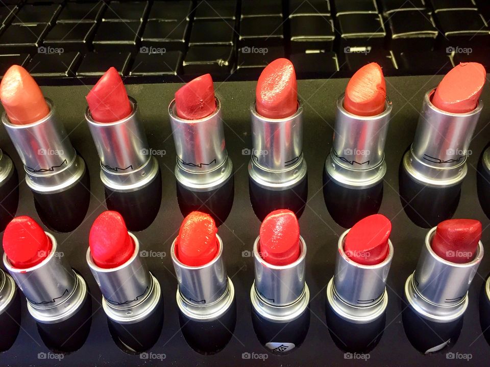 Different shades of red lipstick tester tubes on display at a cosmetic store.