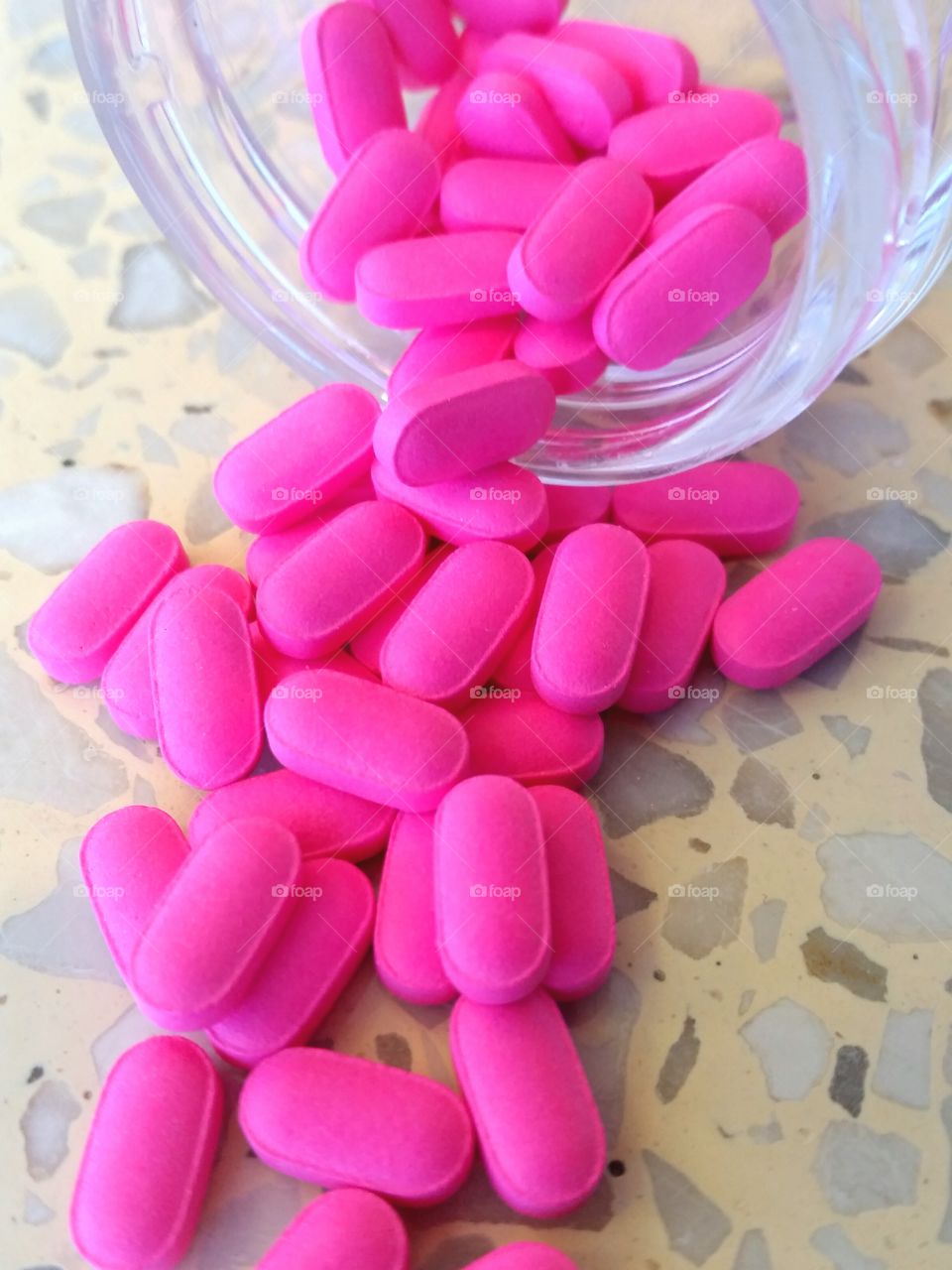 Pink pills tumbling out of jar