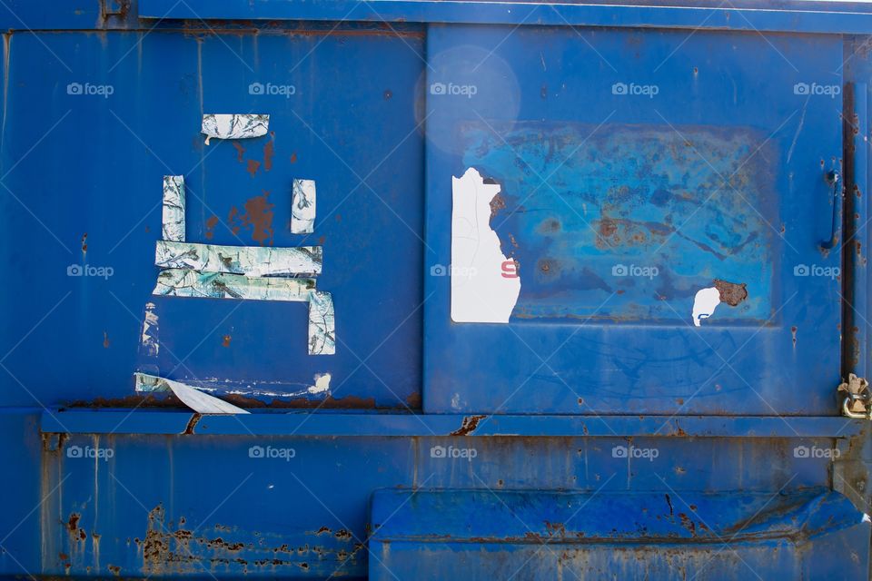 Abstract blue dumpster background on bright sunny day.