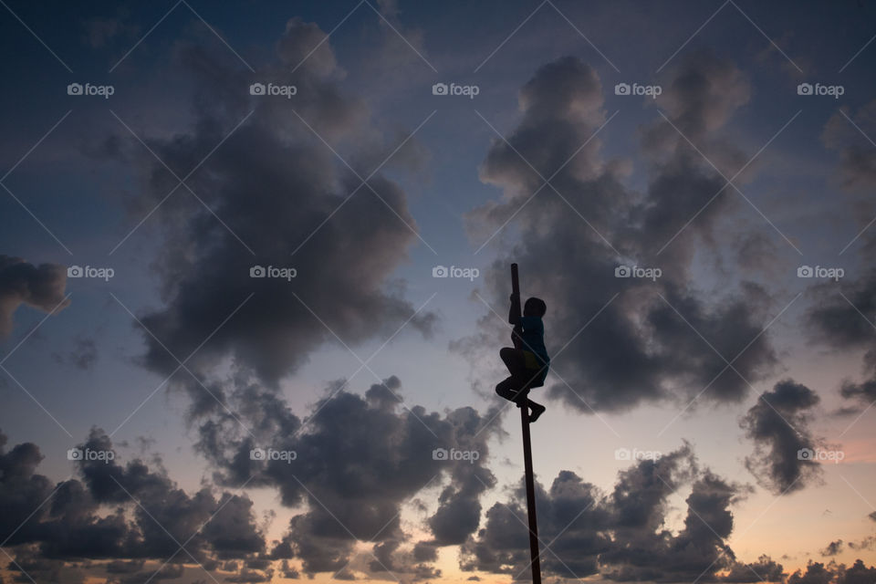 one boy climbing up a pole