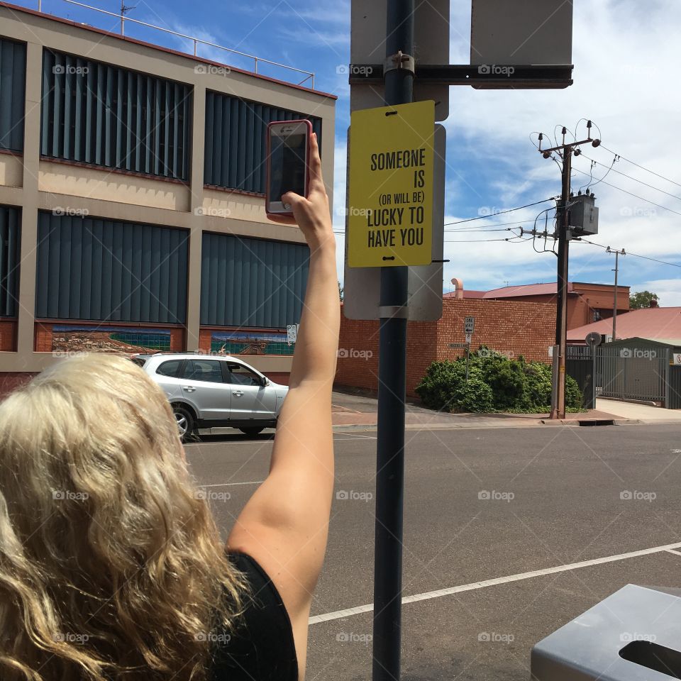 Someone is or will be lucky to have you; young adult female taking photo of street sign