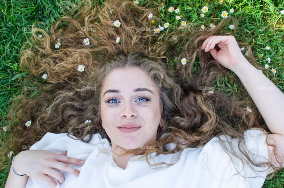 Portrait of a Beautiful Young Girl on Background of Daisies