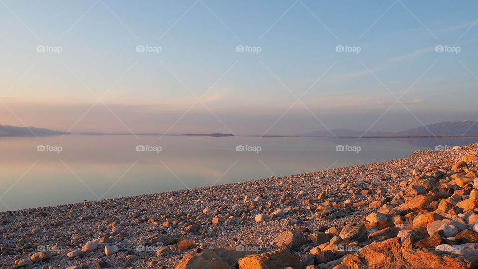 Rocky beach sunset. Calm tranquil waters on eocky beach