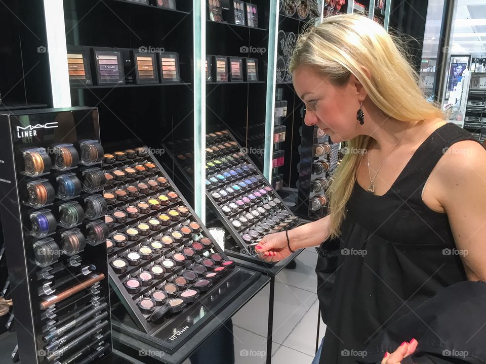 Woman 30 plus years is lookng at makeup products in a taxfree shop at Copenhagen airport in Denmark.