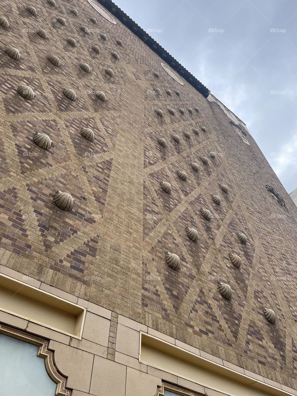 Looking up the side of a tall building with repeated diamond patterns and shells.