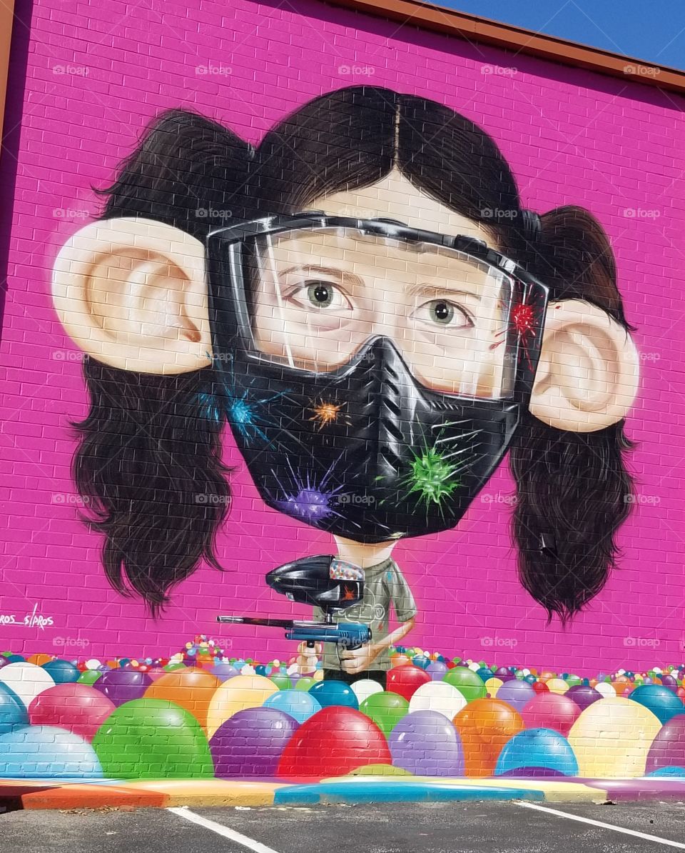Fun paintball mural on building bright pink background.
