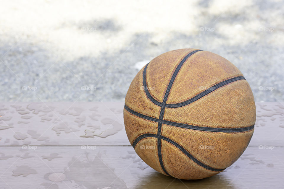 Basketball leather on the wooden chair with water droplets.