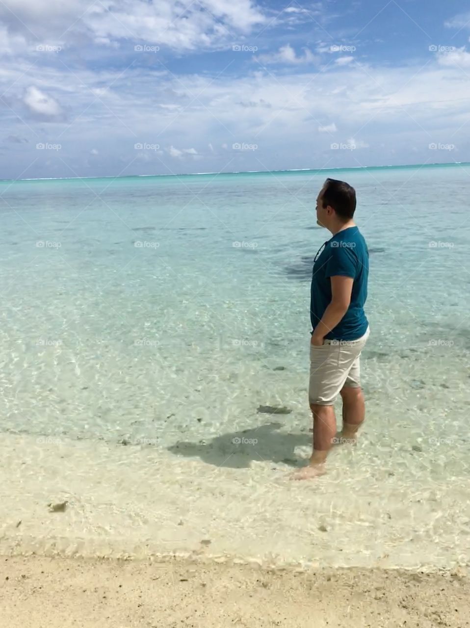 Man looking out at the beach in beautiful clear waters