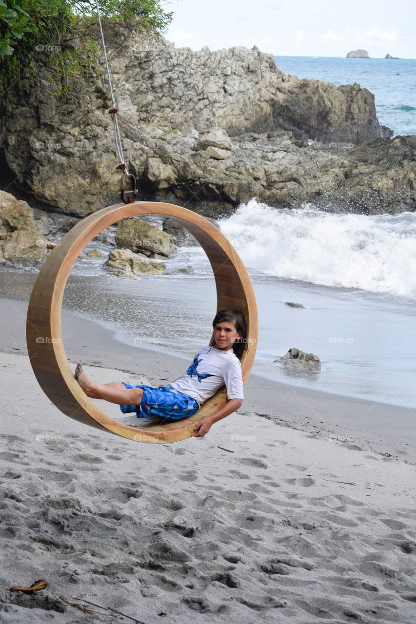 Boy on rope swing at beach