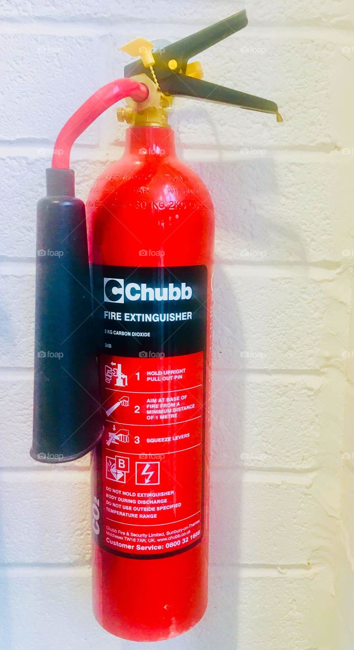Red fire extinguisher on wall by Chubb