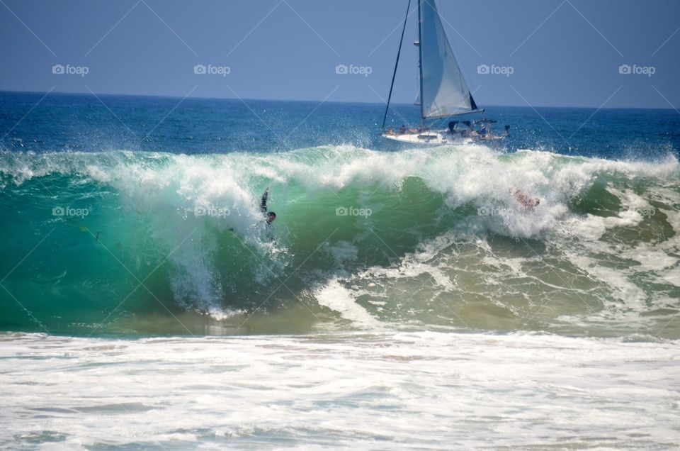 Come Sail Away. Body surfers lined up to tackle the large waves as the sailboats drifted by..
