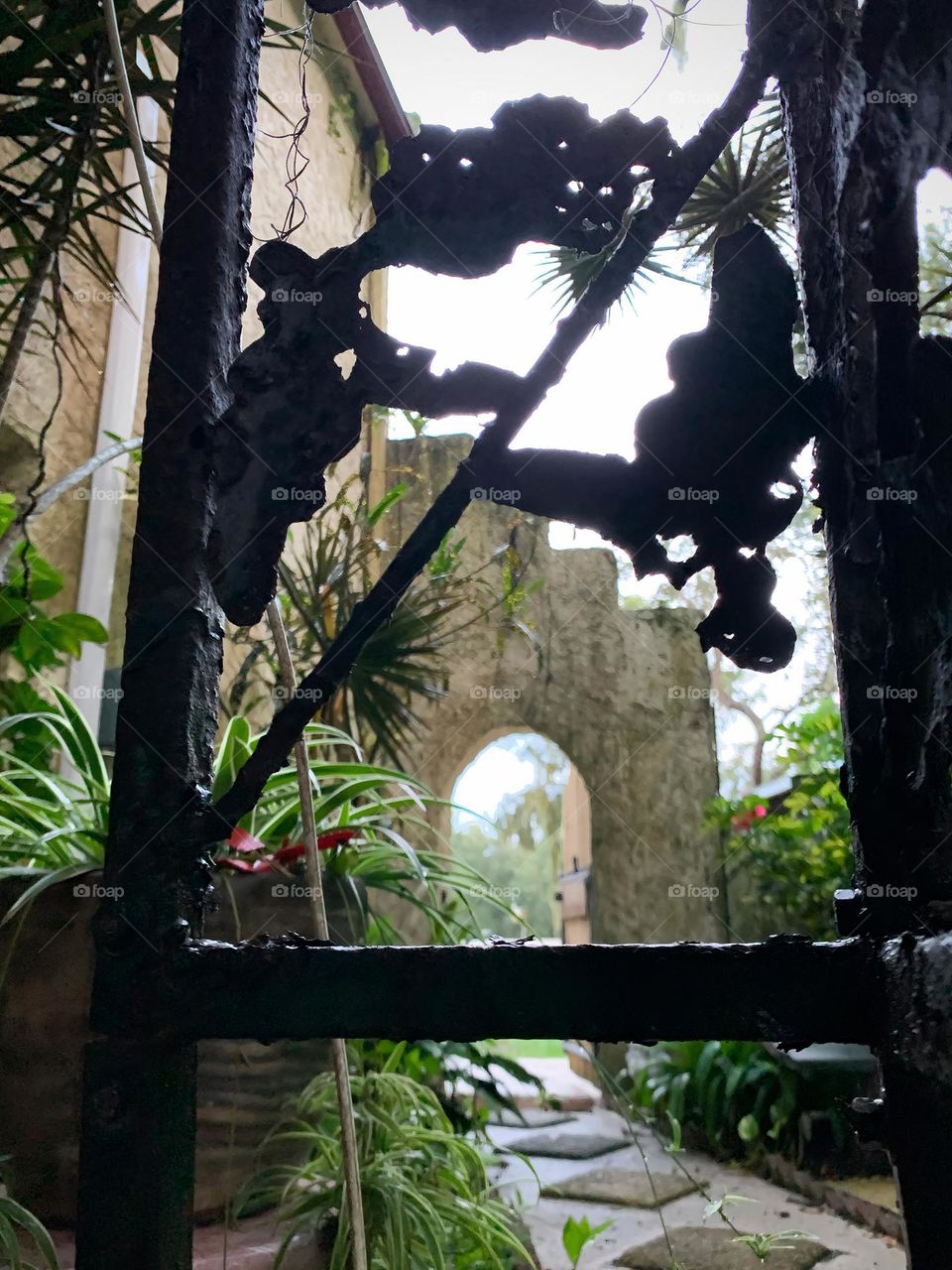 Architectural residence backyard with decoration and black frame structure on a porch and view of an entrance opening with antique style doorway, view on both side of the wall Spanish style house from the early 1900s.