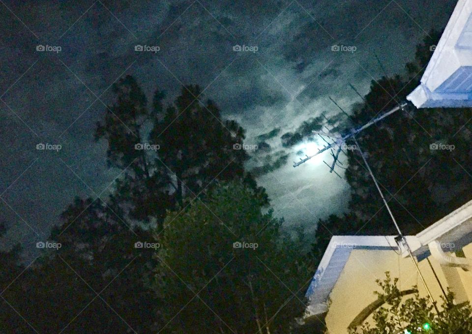 Moon Night thru Antenna . Moon Light on a cloudy night with house and TV antenna in foreground 