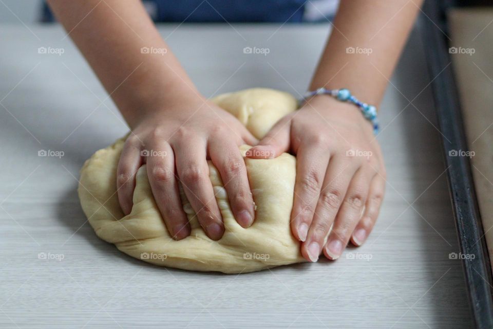 Child's hands are mixing bread dough