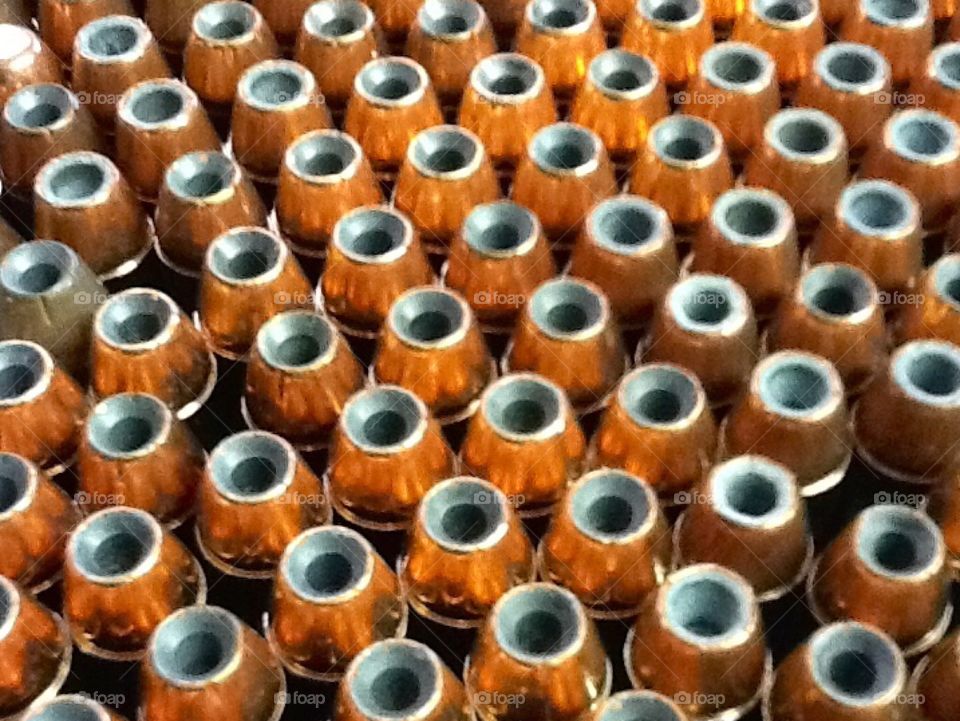 Hollow point bullets lined up on their end with tip pointing up. Cool contrast between the copper and lead.  The arrangement fills the view with bullets everywhere. 