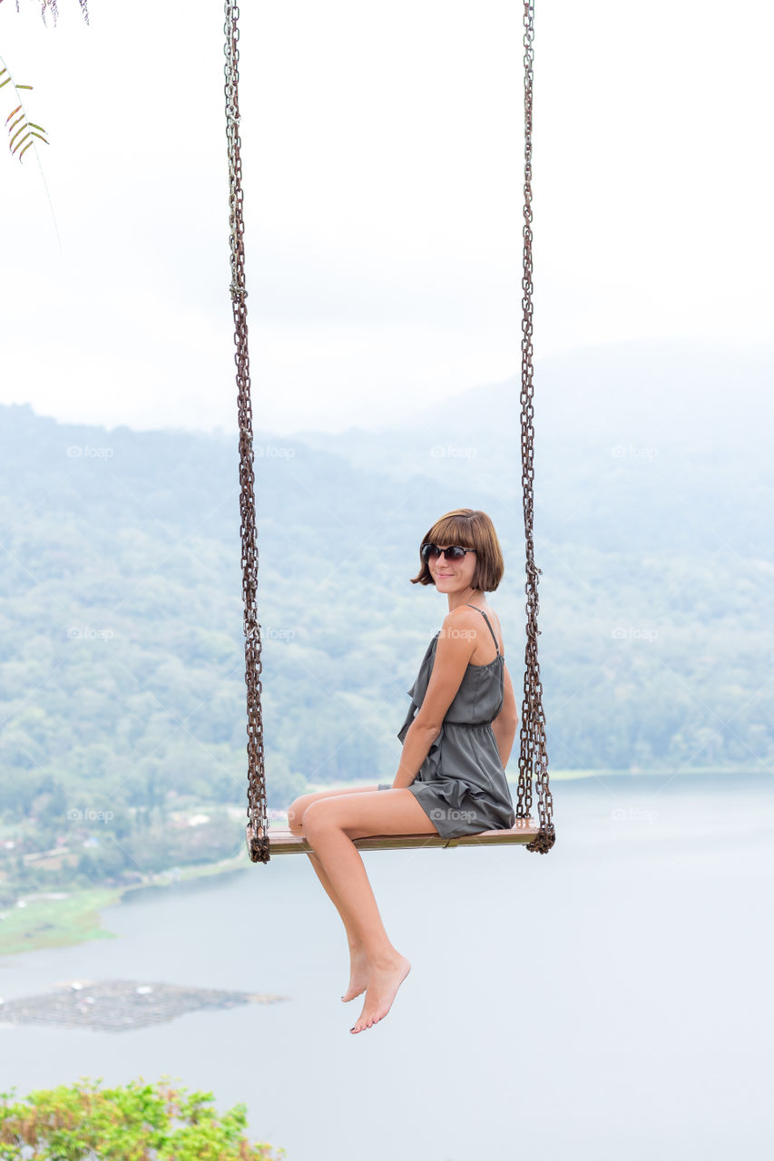 Girl on a swing overlooking the lake and mountains. Bali island.