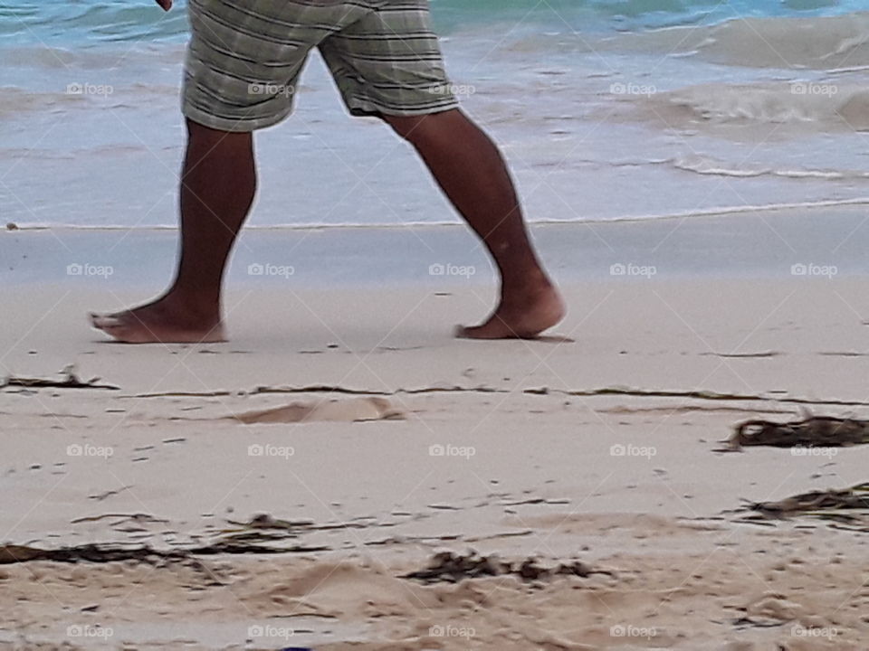 a tourist walks along the beach his feet