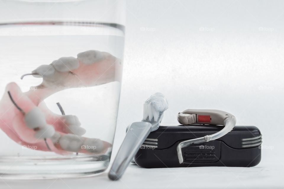 dental prosthesis in a glass and a toothbrush, hearing aid