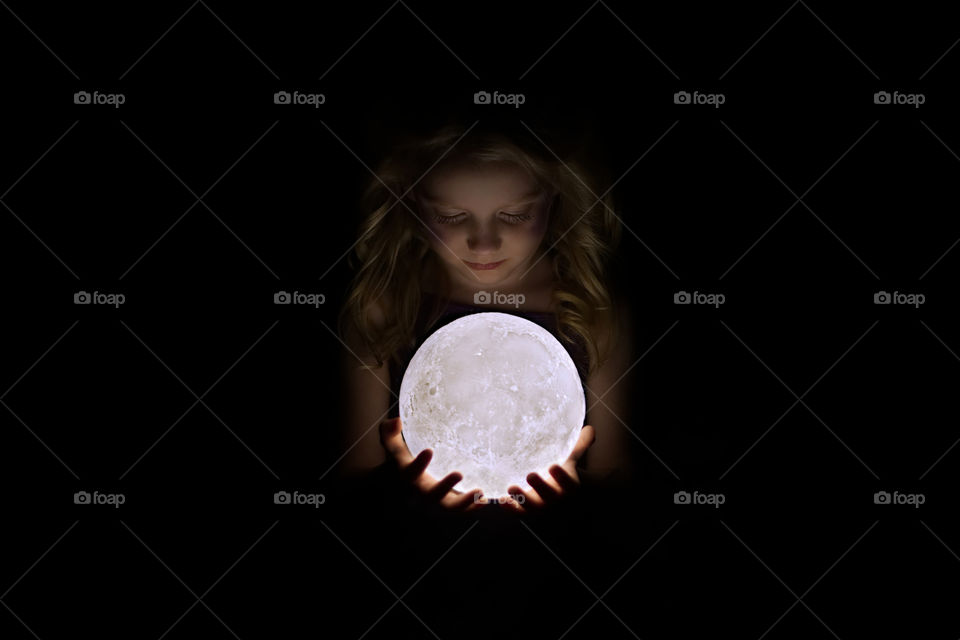 Little girl holding the moon in her hands