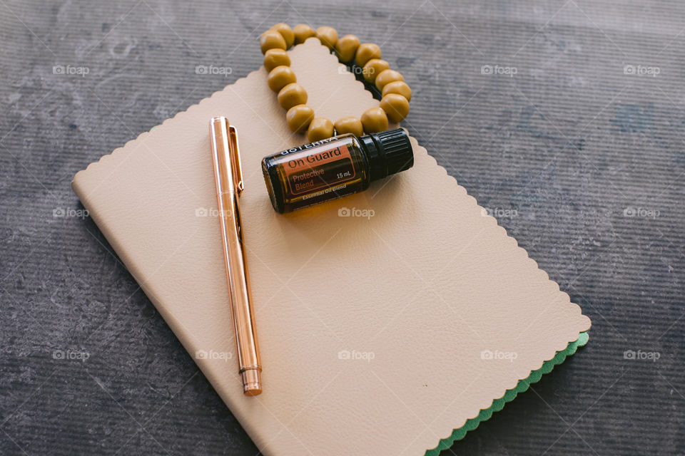 On guard doterra essential oil bottle on cream notebook with rose gold pen and mustard bead bracelet 