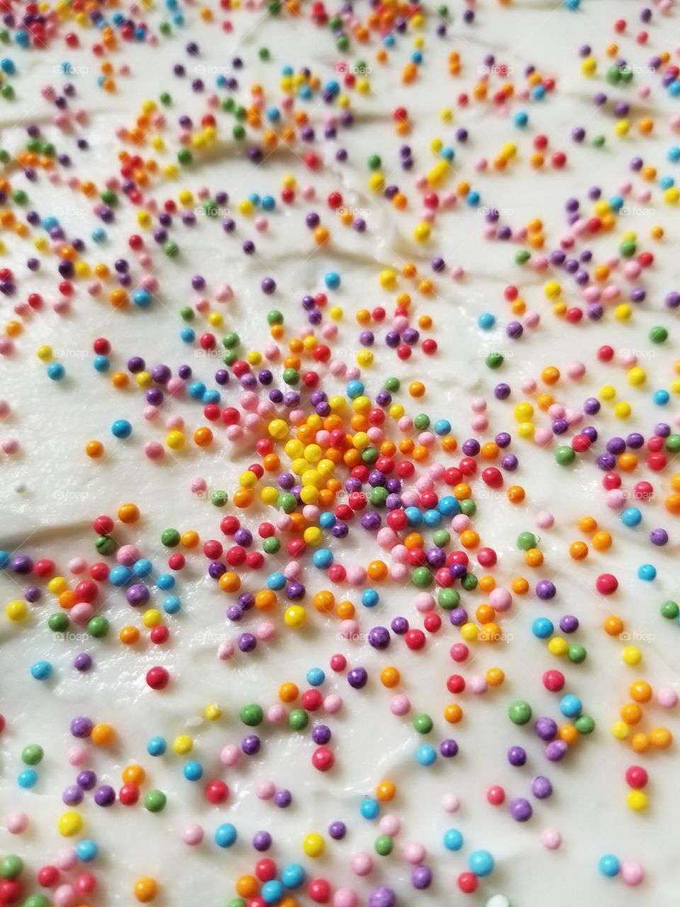 Colorful Sprinkles on the White Icing of a cake is a small glimmer of happiness