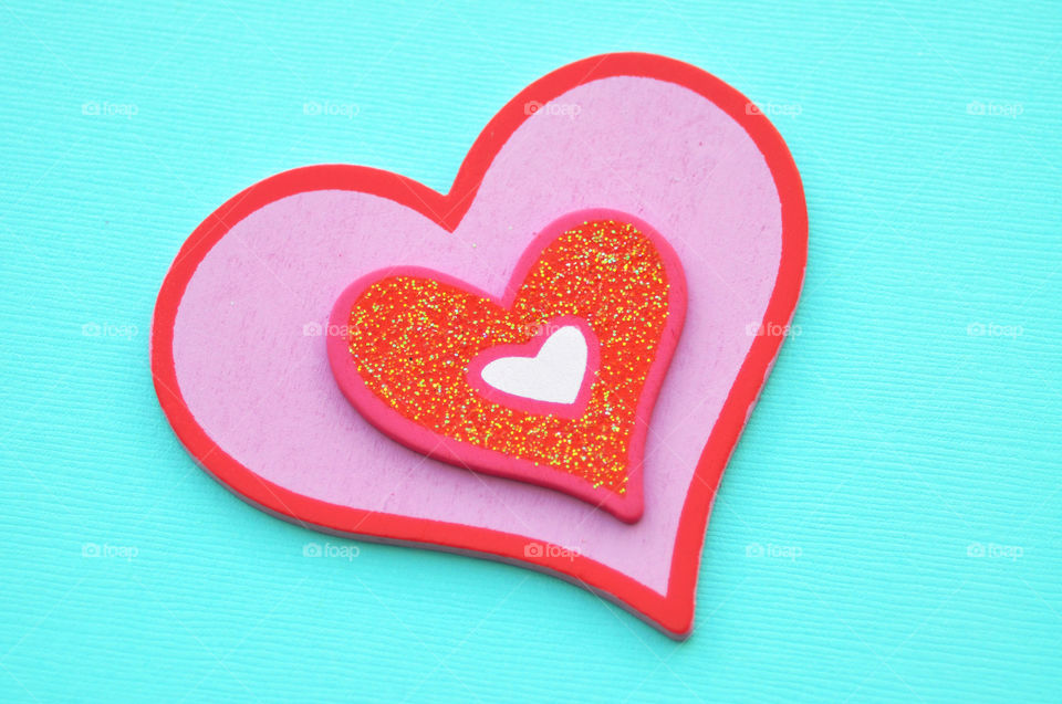 Love. Pink heart against a turquoise background.