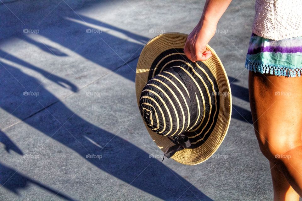 Hats off- a woman walking with a sun hat. 