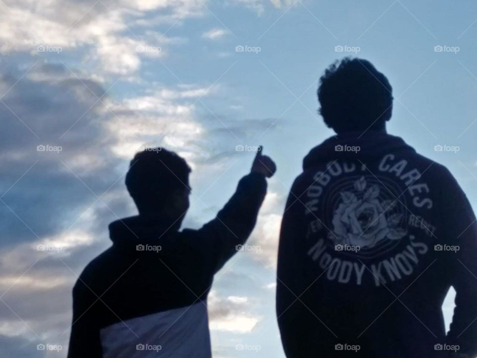 Two young men looking at the horizon and clear blue sky.