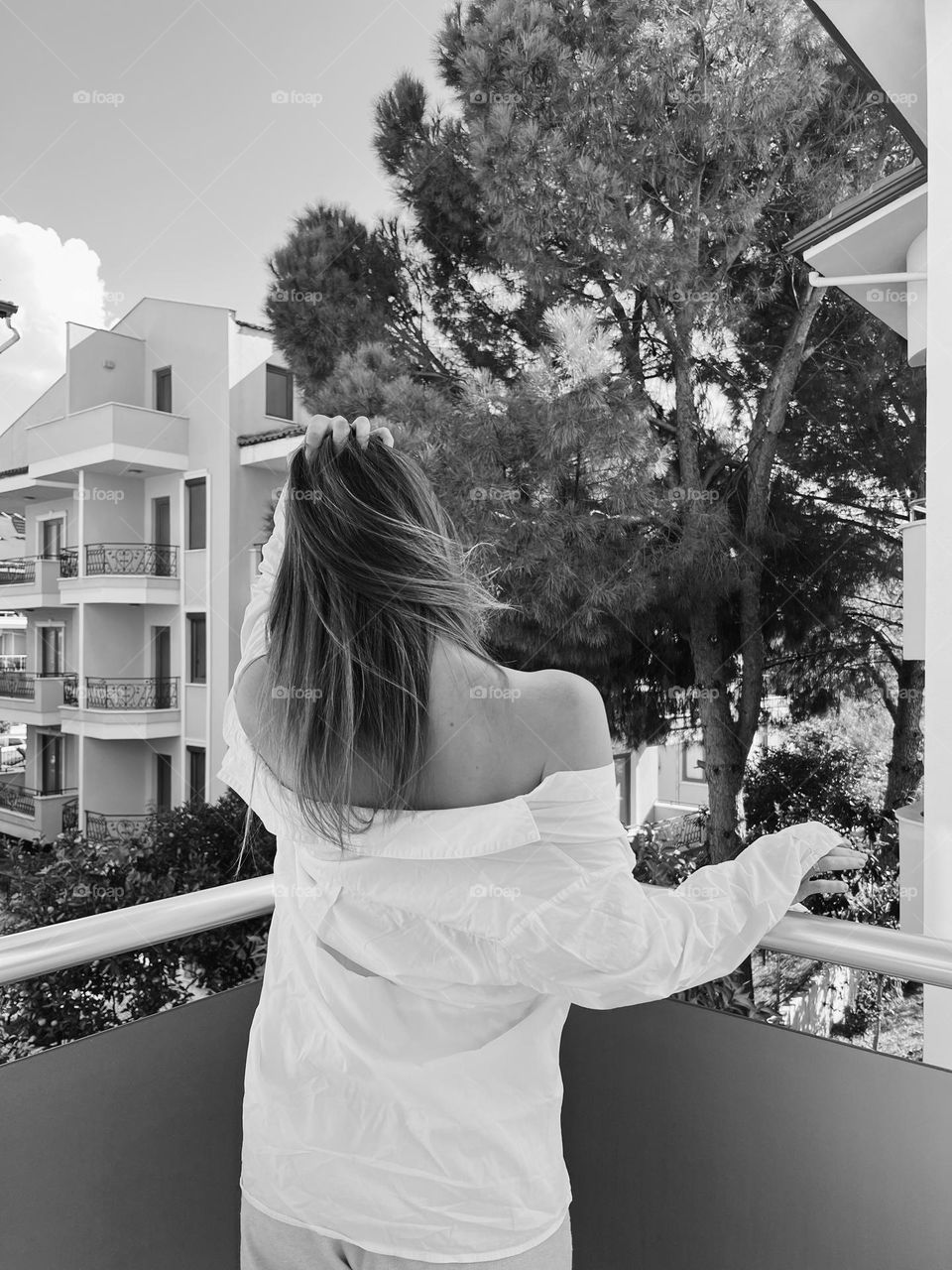 Woman back on balcony with wind in hair