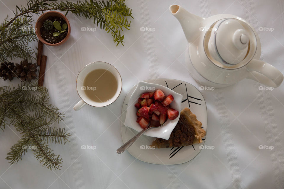 Tea, strawberries and pecan pie in a festive flat lay, beside a teapot