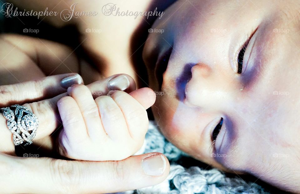 Newborn baby holding mother hand