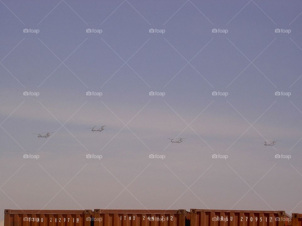 chinooks above shipping containers