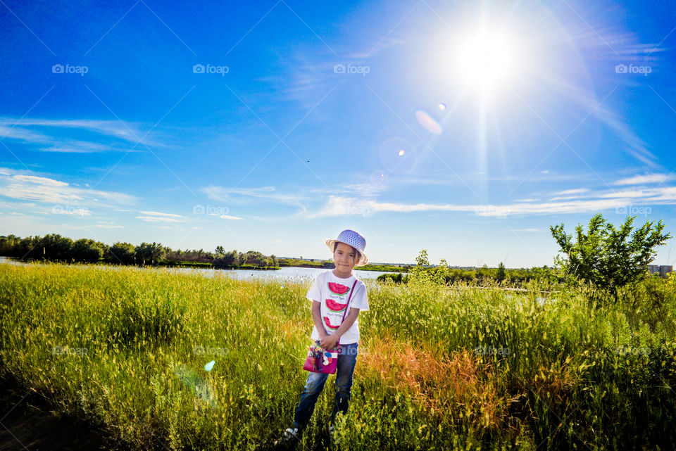 девочка в шляпе стоит под лучами солнца