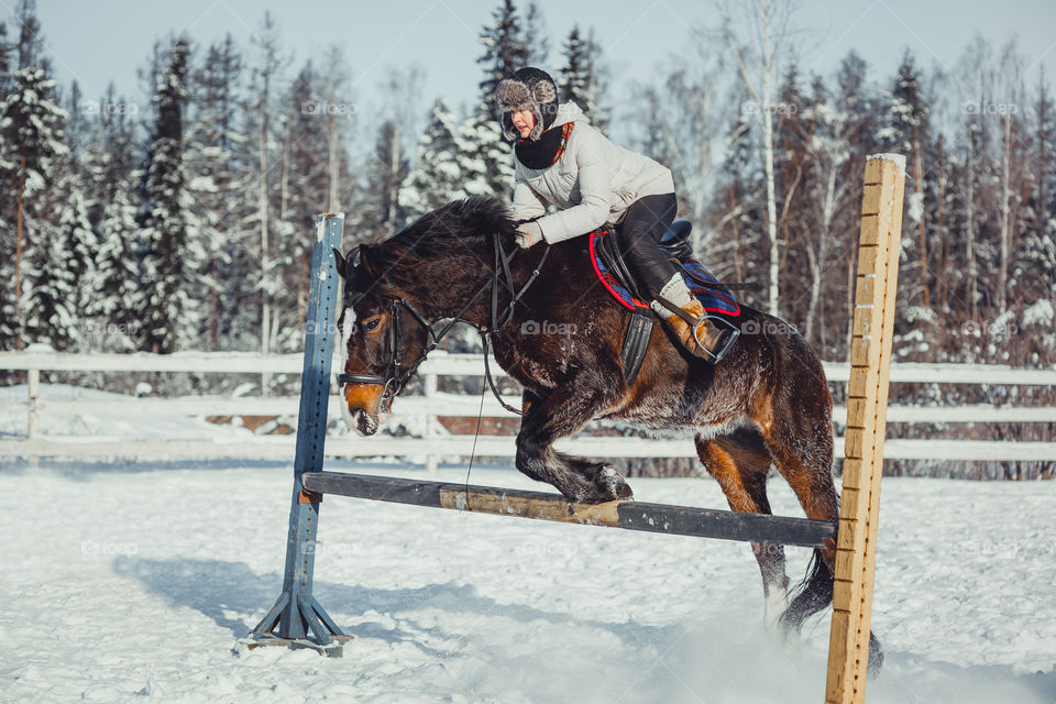 Teenage girl horseback jumping at cold winter day