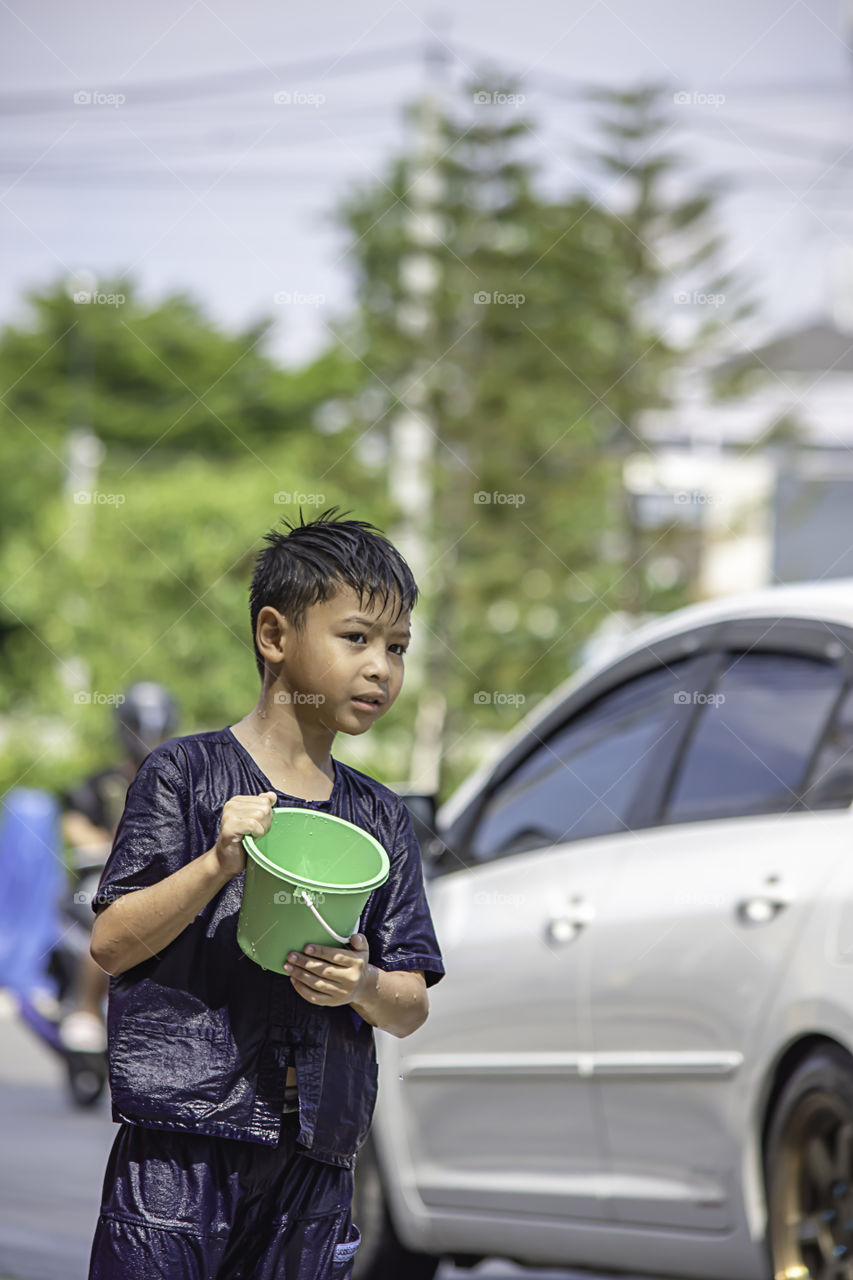 Asian boy holding Plastic bucket play Songkran festival or Thai new year in Thailand.