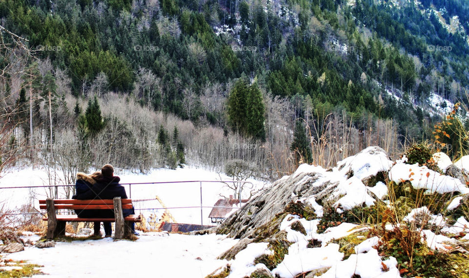 Couple sitting on a bench in snowy mountainous region