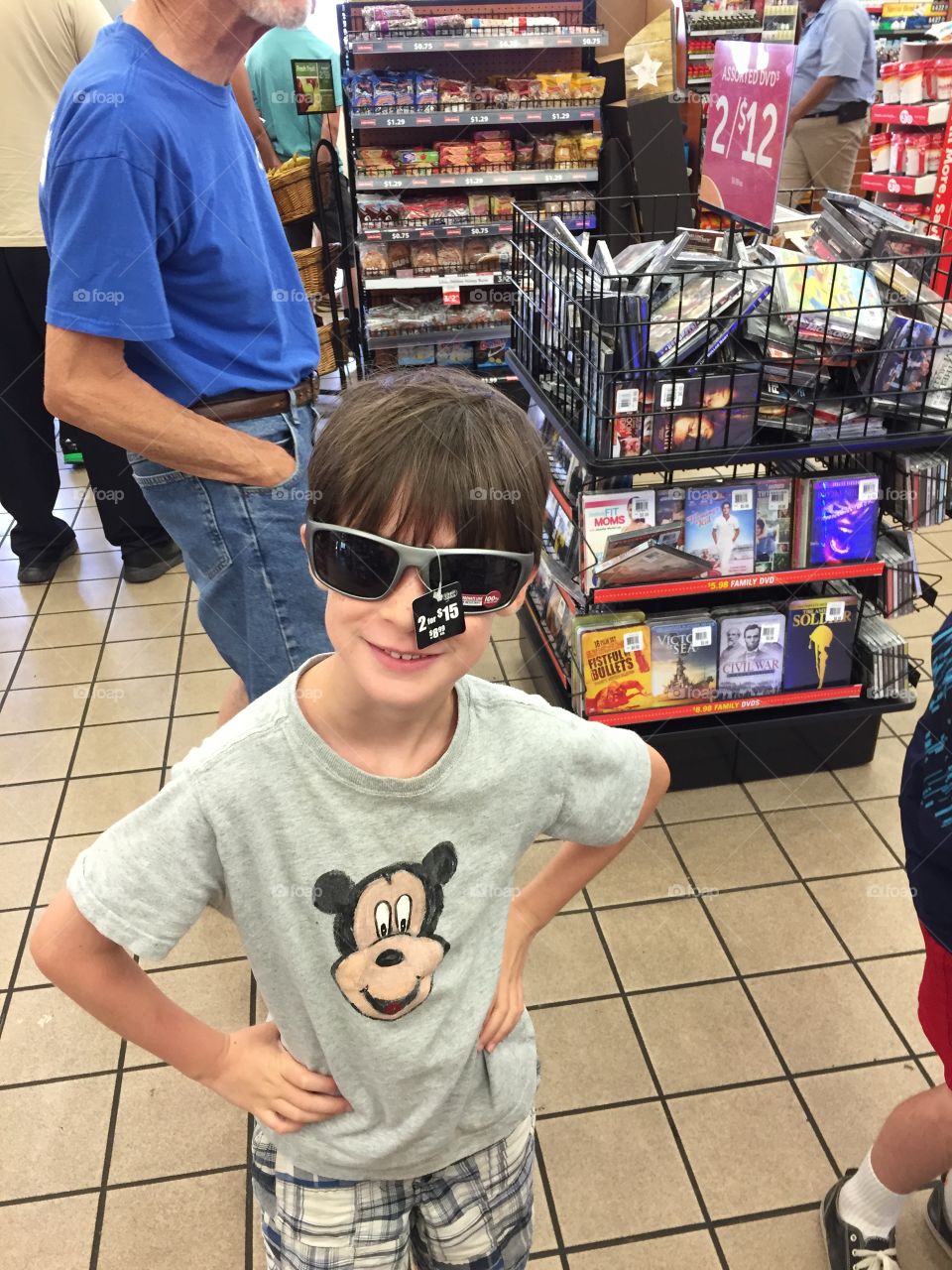 Six year old boy trying on some sunglasses in the store.