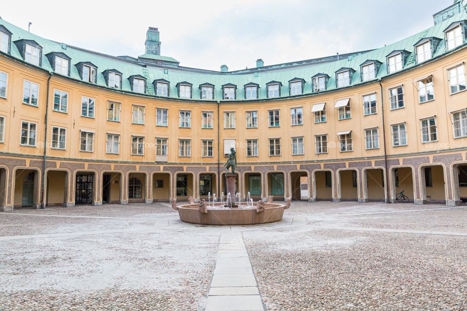 Curved architecture with vaults and old copper roof, fountain in the middle, building in the city of Stockholm Sweden 