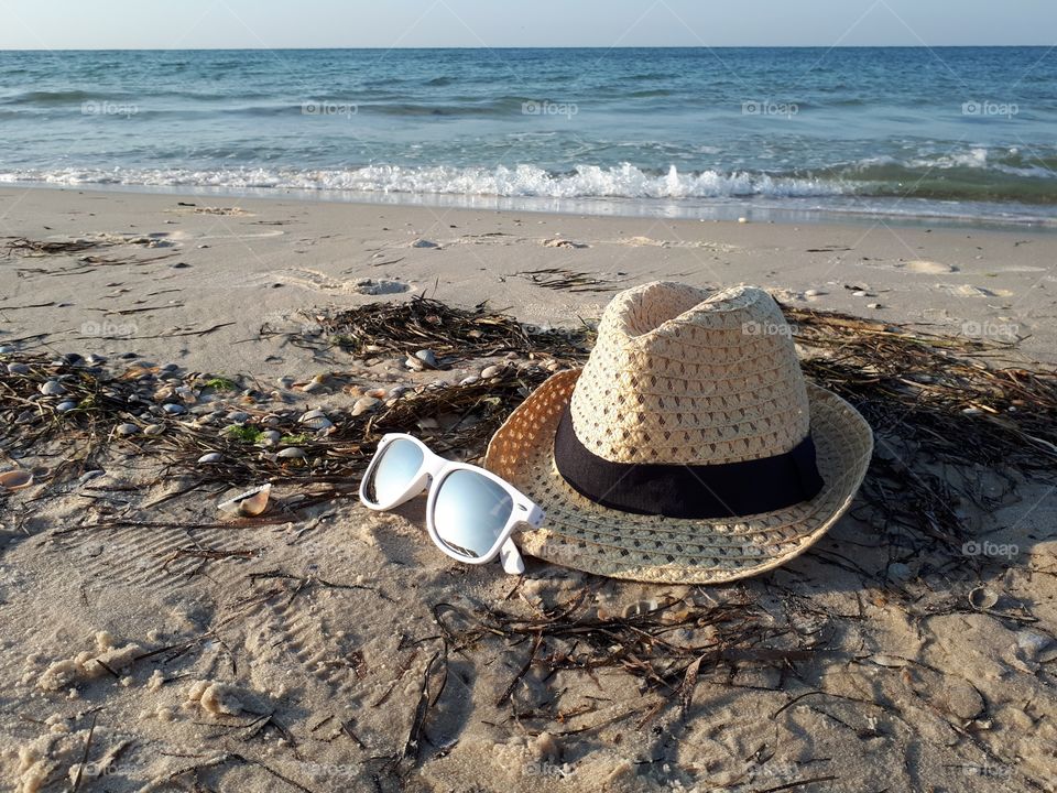 Straw hat and white sunglasses at the sand beach