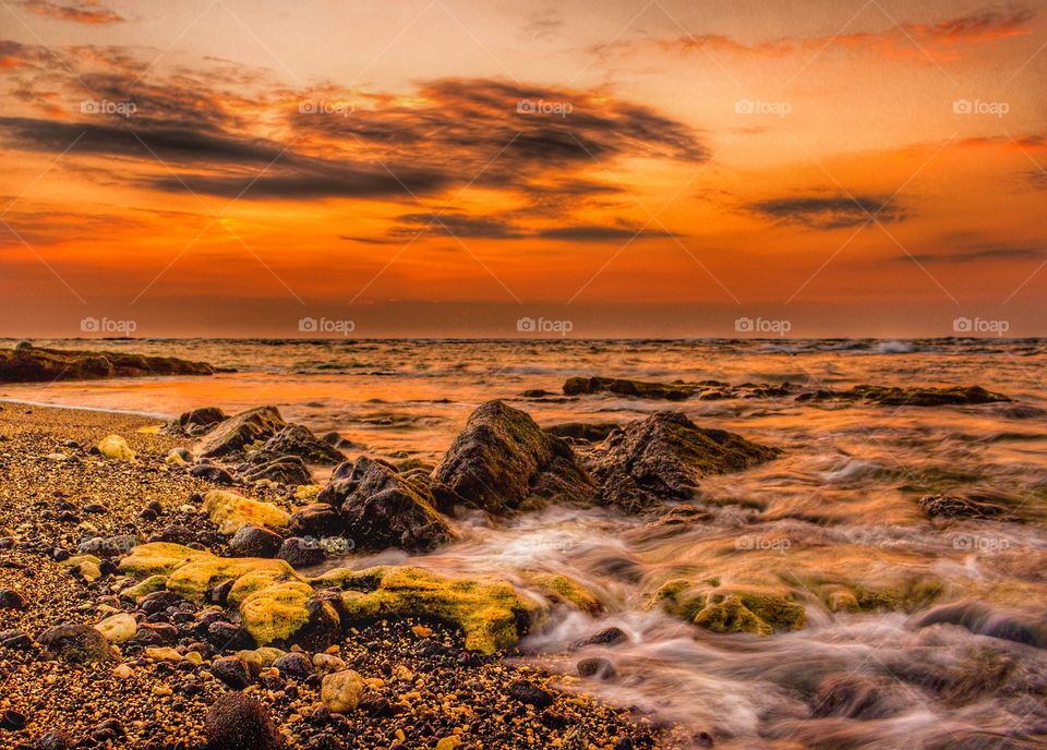 Rock on beach at sunset