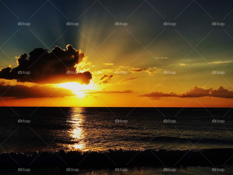 Glorious golden sunset and dark glowing clouds over the ocean.