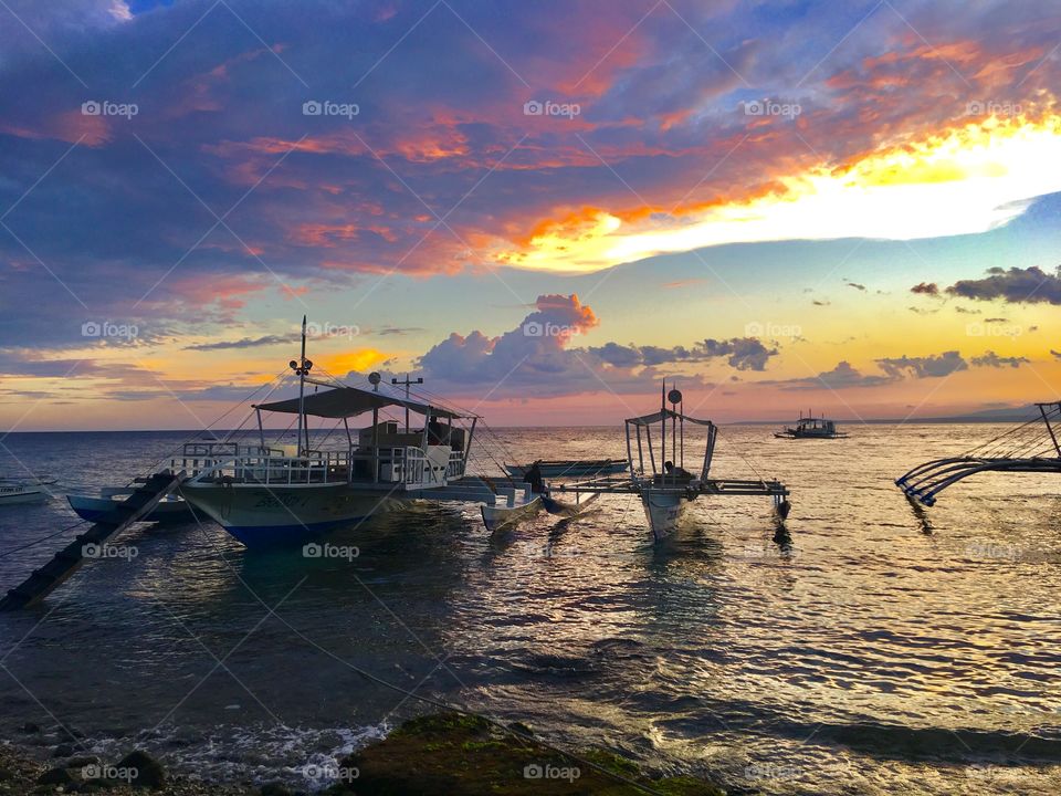 The name "Apo" was derived from a Filipino word for "old man". The Boats are waiting for the island hopping with the beautiful sunset background.