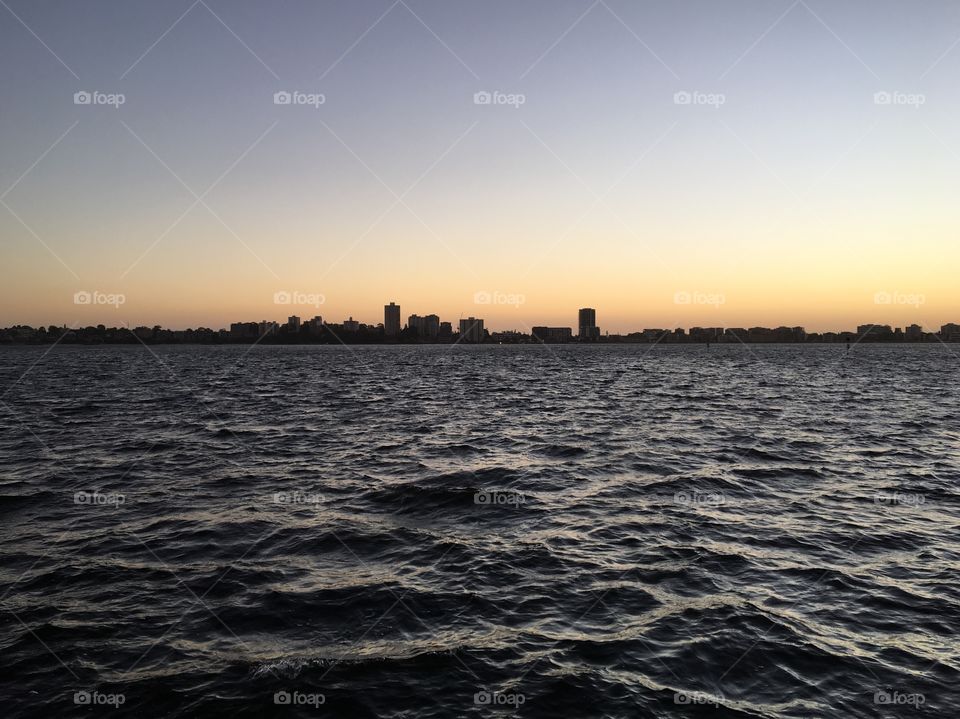 The view of riverside at the time of the sunset. It can be seen high-rise buildings.