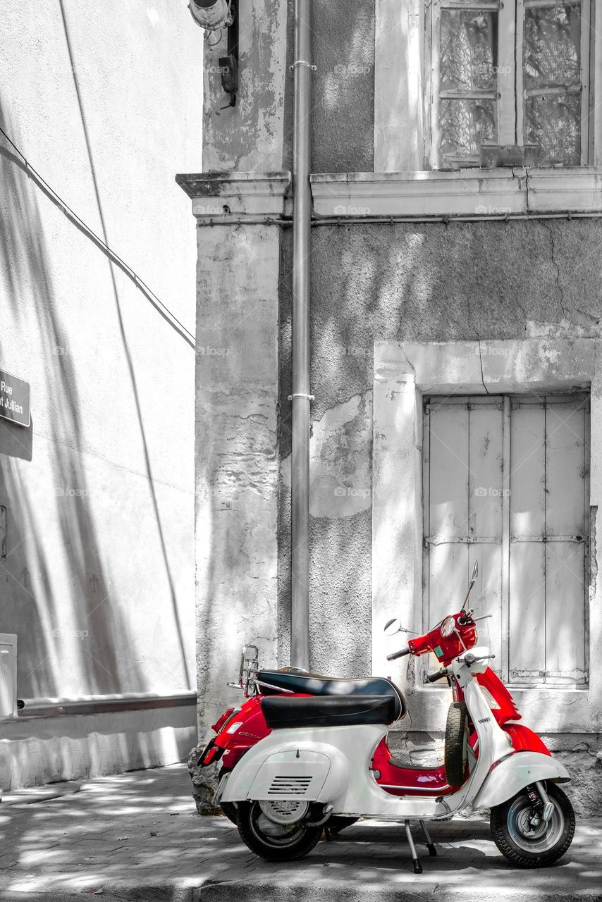 two scooters red and white parked on a pavement in front of a house in a French city