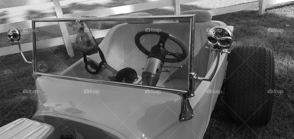 A convertible classic hot rod  in black and white because I think the detail of the skull rearview mirrors stand out